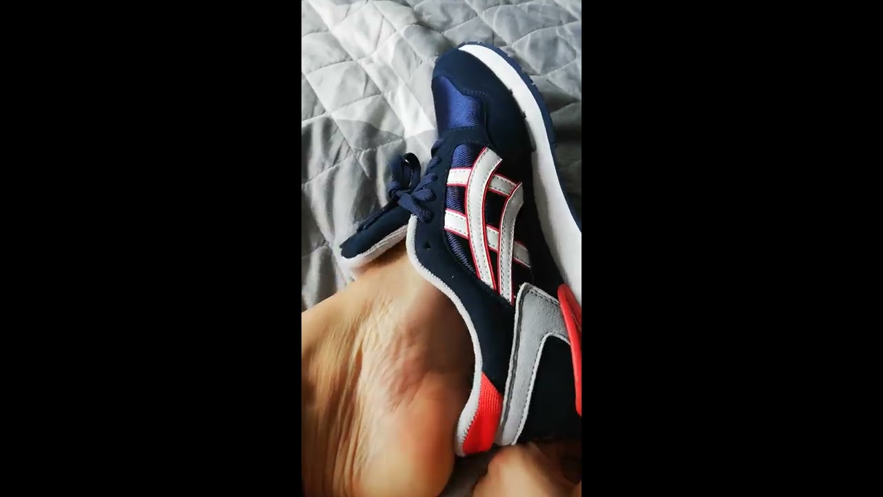 Bare feet in Asics Gel Atlanis on bed shoeplay