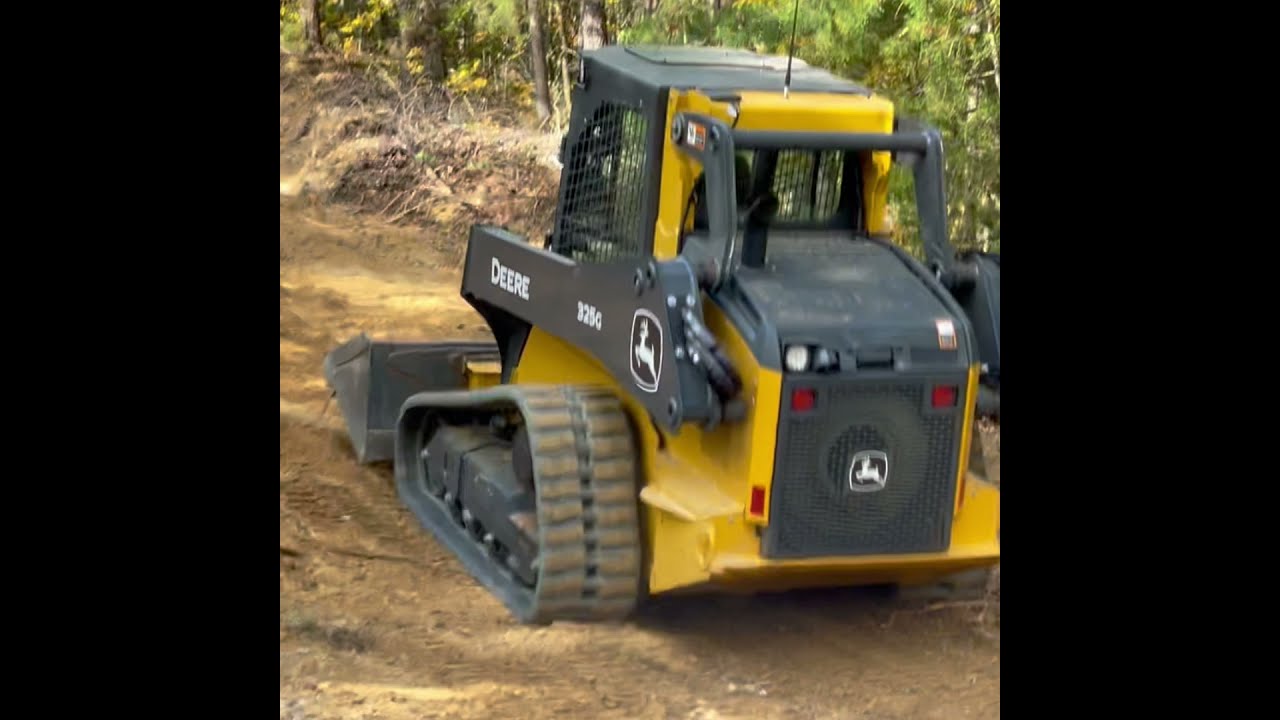 John Deere 325G grading some roads on the side of a mountain