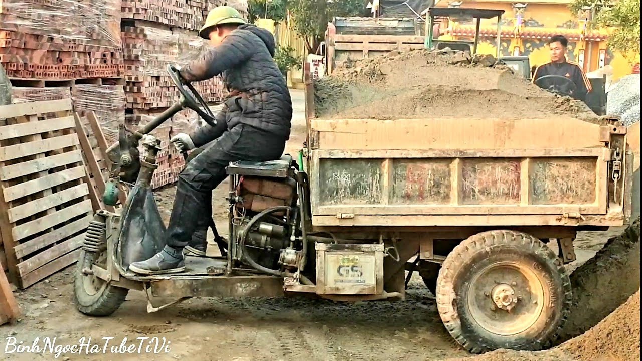 Three-wheeled farm vehicle carrying sand
