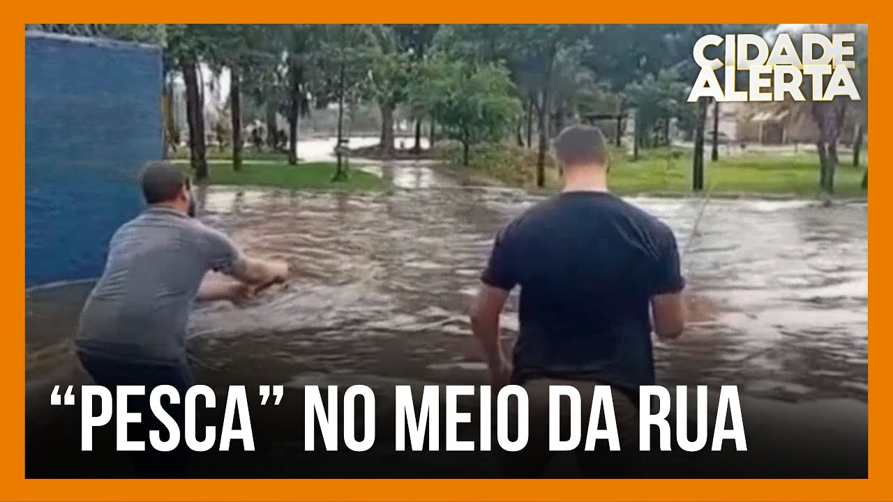 Homens “pescam” em rua tomada pela água da chuva, em Patos de Minas