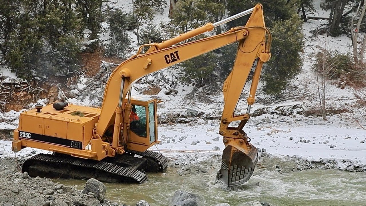 CAT 235C excavator operator  digs thru rock and boulders to divert creek