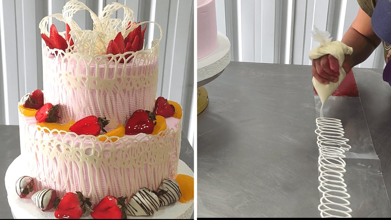 Hermoso pastel de dos pisos enrejado con chocolate blanco y adornados con frutas