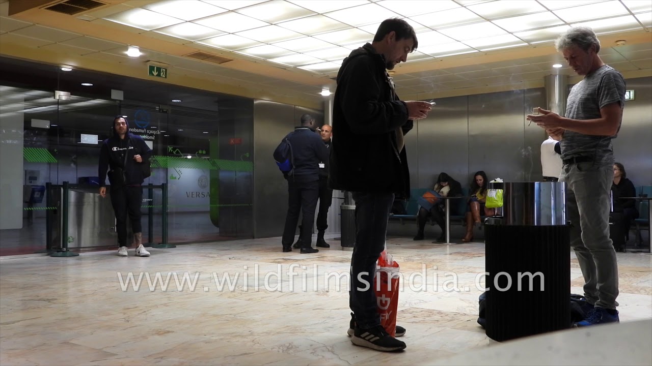 Passengers smoke inside the smoking area of Terminal 1, Lisbon Airport