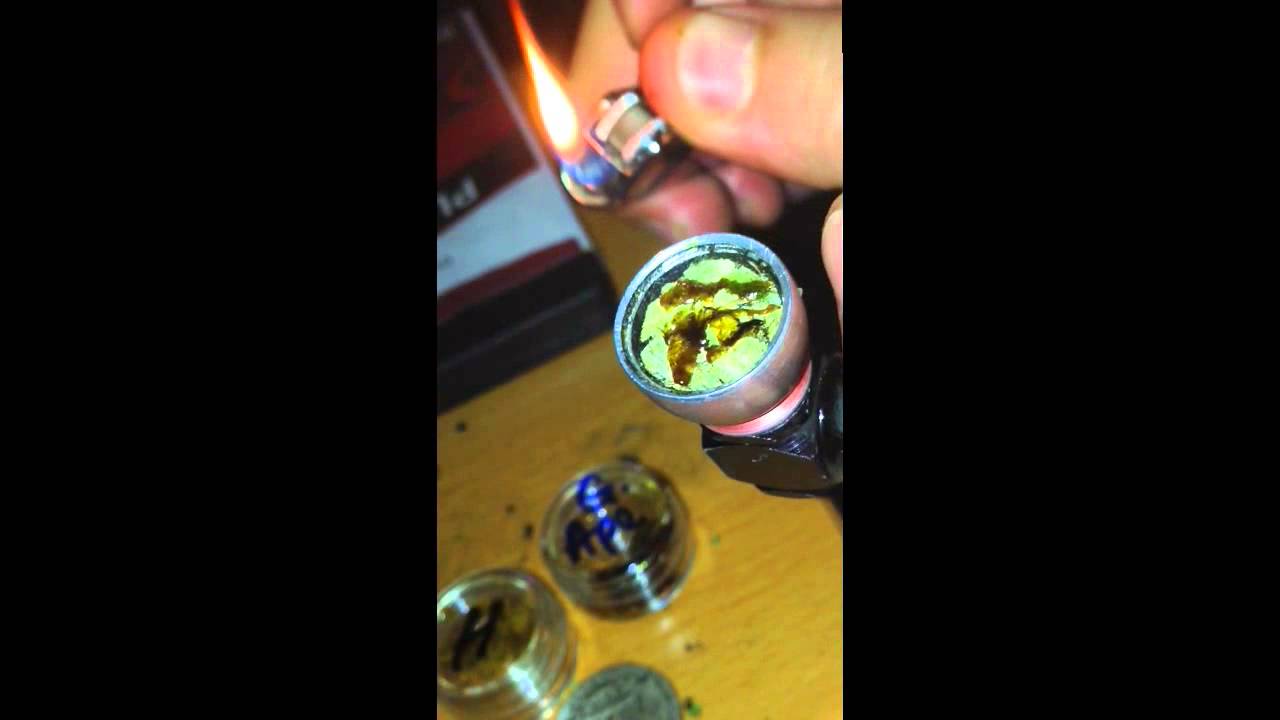 Smoking cannabis shatter wax, glass hash oil, with bud