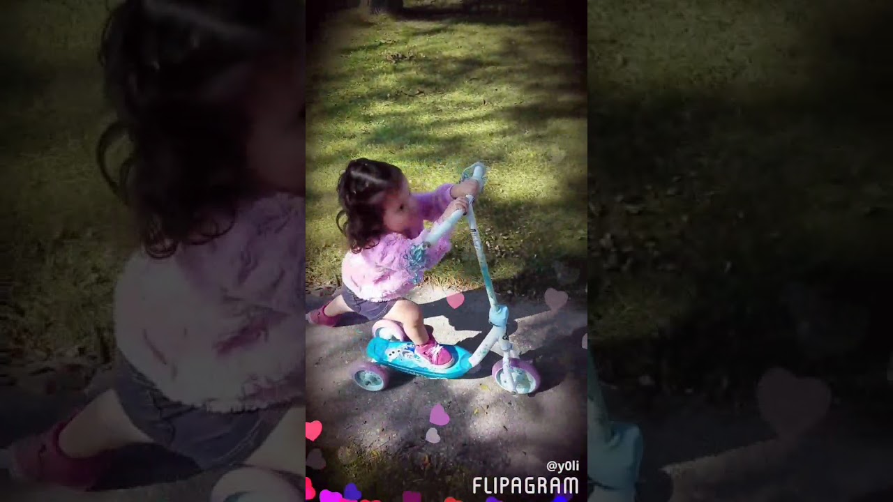 little girl learns how to ride a scooter.
