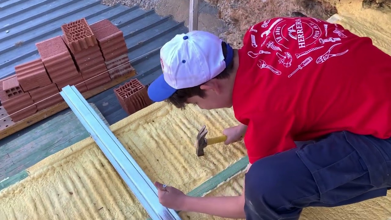 Poniendo las correas metálicas en el tejado para poner la chapa sándwich imitación teja.