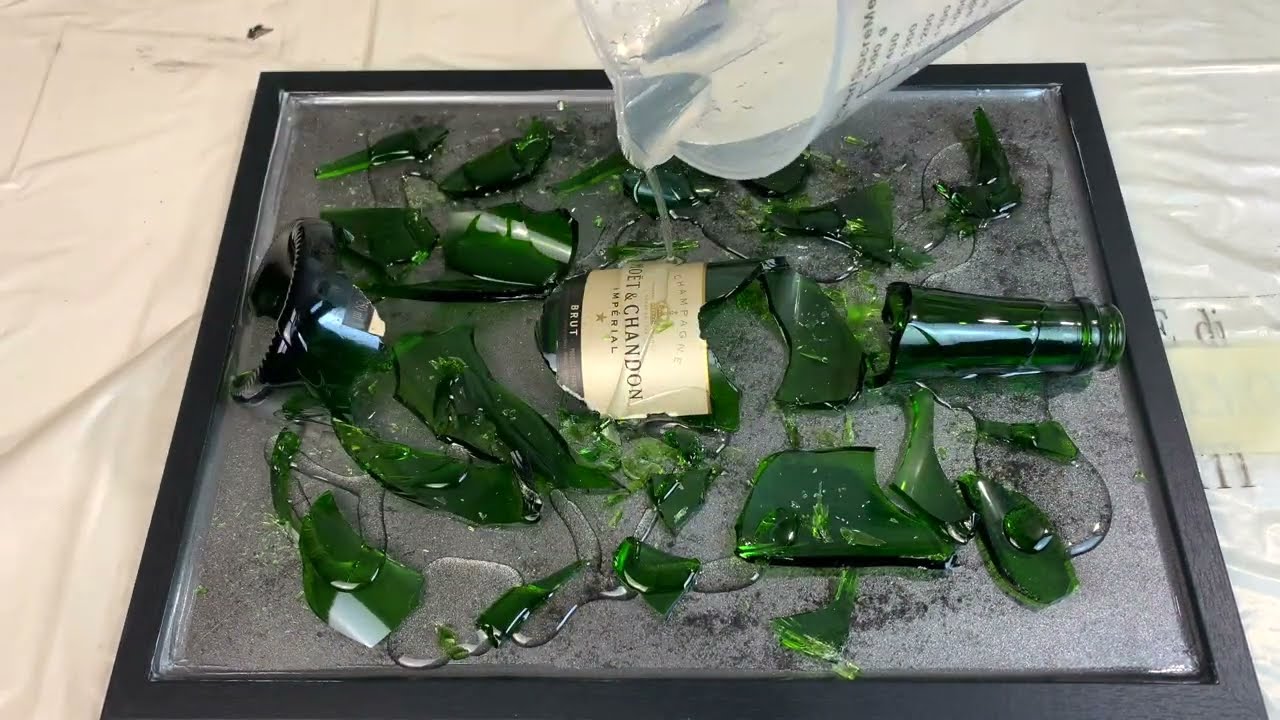 Arte moderna spaccando una bottiglia di champagne su un quadro nudo in Sughero e aggiungendo Resina