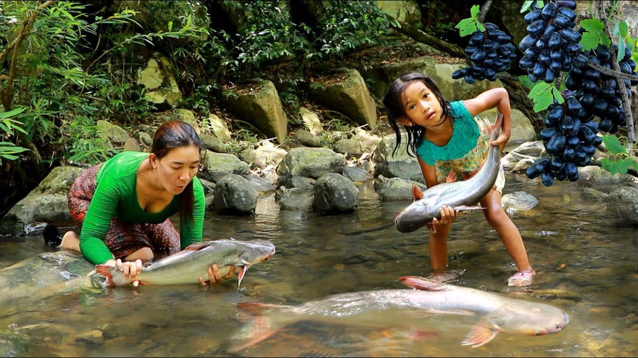 Mother with daughter catch big fish in river and pick black grape fruit in forest eating delicious