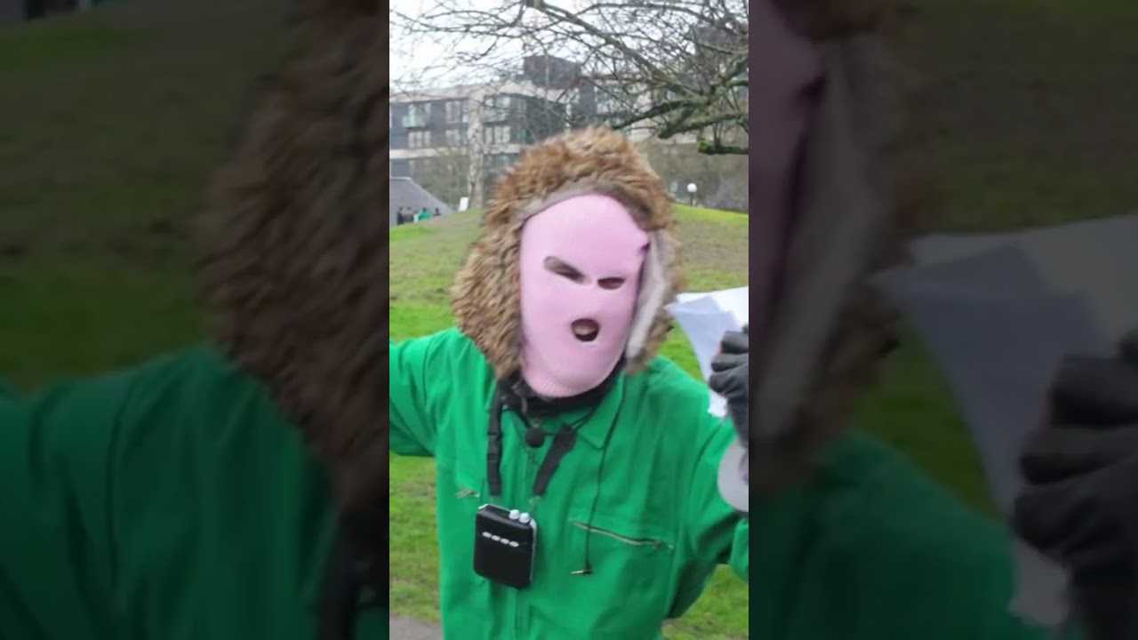 Masked protester at anti ice rally voicing opinion over loud speaker