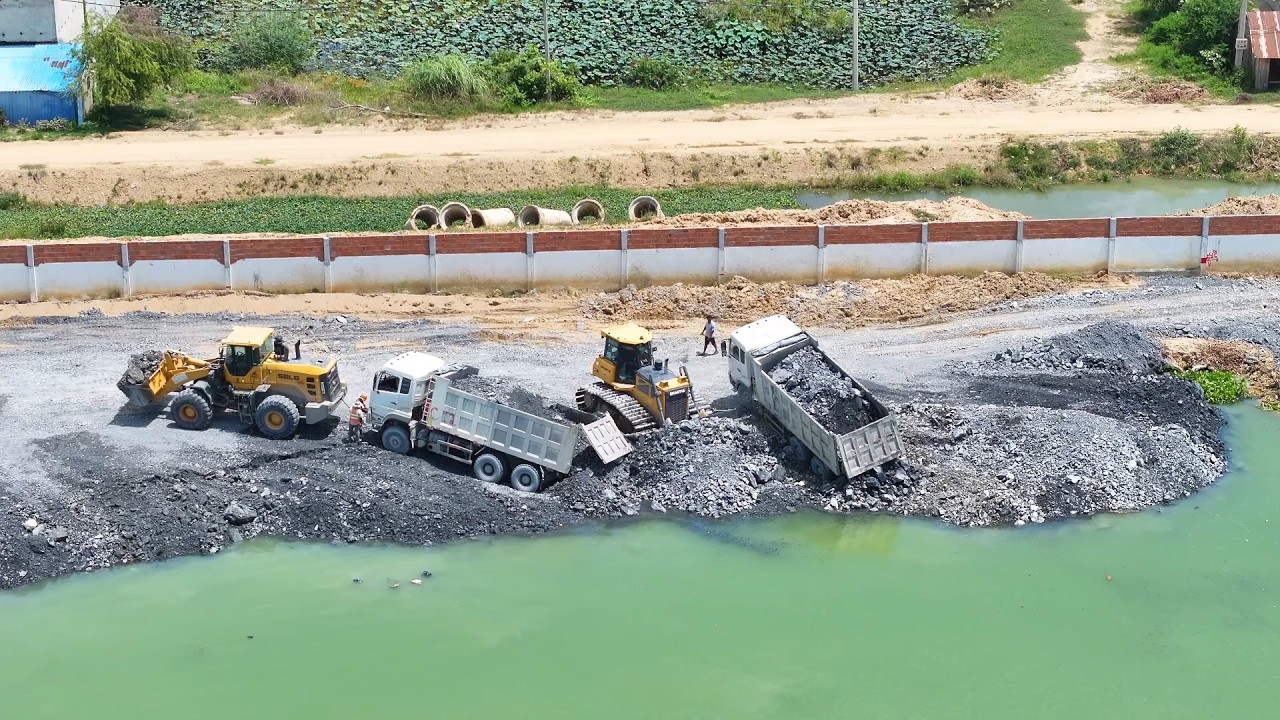 Interesting Shantui Bulldozer Pushing Rock Filling a Lake With SHACMAN Trucks Unloading Rock+Sand