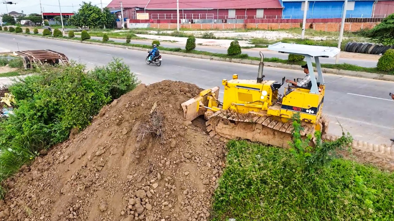 Great bulldozer pushing new project with dump trucks filling land