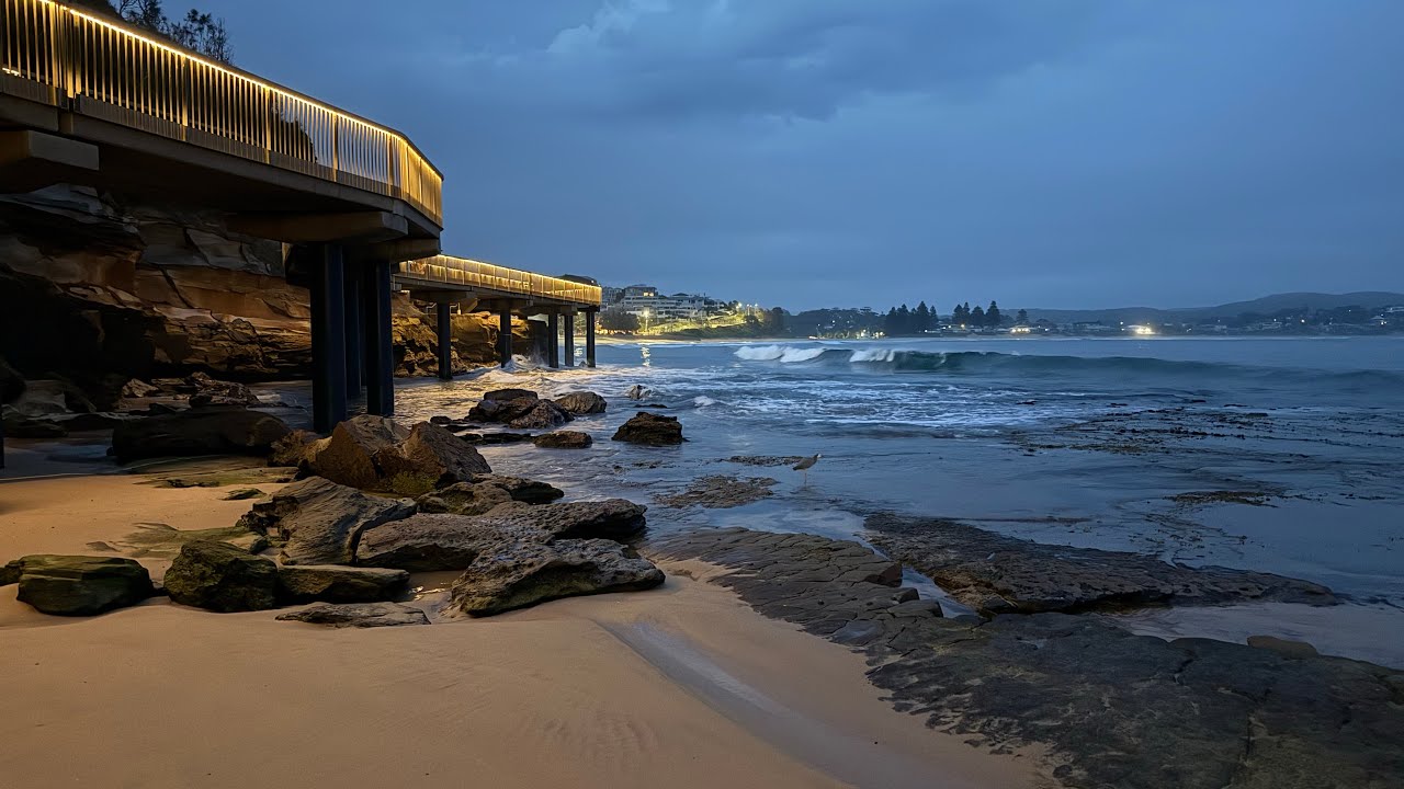 Early morning at Terrigal. Grey and humid. Reflections. Lighted boardwalk and Pavilion. 