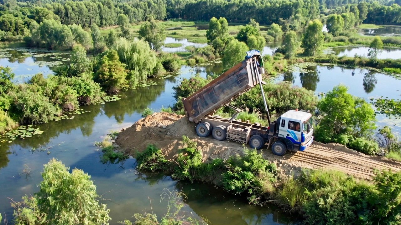 Nicely Skill Machinery on Road Building Dump Truck Unloading Dirt Moving all into Water By Dozer 