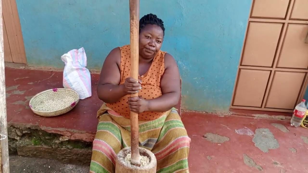 Milling maize in a traditional way using a wooden motor and piston to prepare a traditional meal 