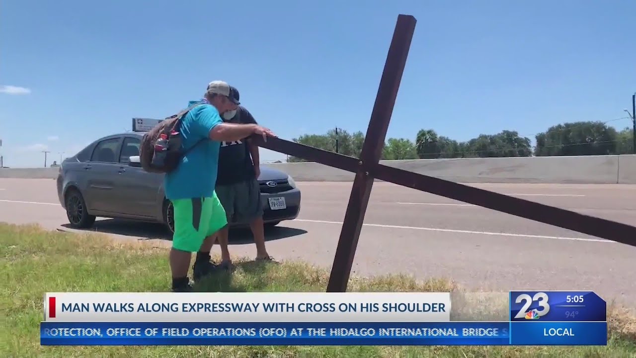 Man walks with cross on along expressway