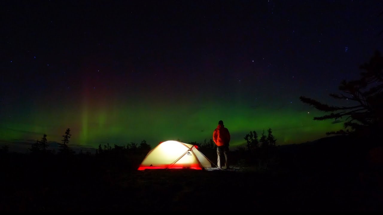 Mountain Top Camping Under Northern Lights Beside Cliffs