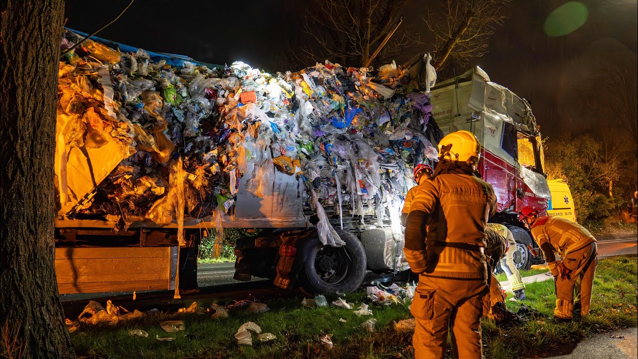Vrachtwagen met huisvuil opengereten na botsing tegen boom, N348 bezaaid met afval