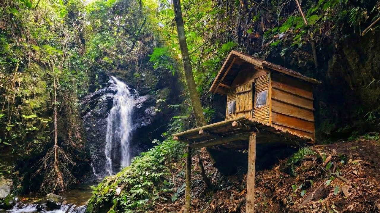 building a wooden house on a cliff near a waterfall.