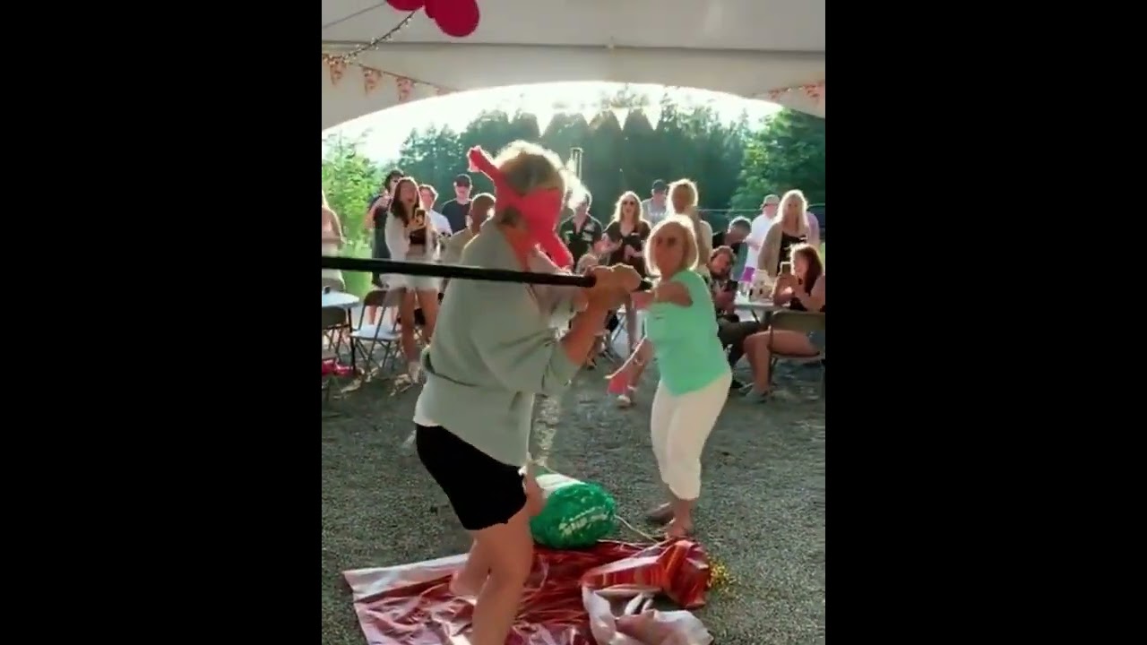 Standing in front of a blindfolded person trying to hit a pi&ntilde;ata.