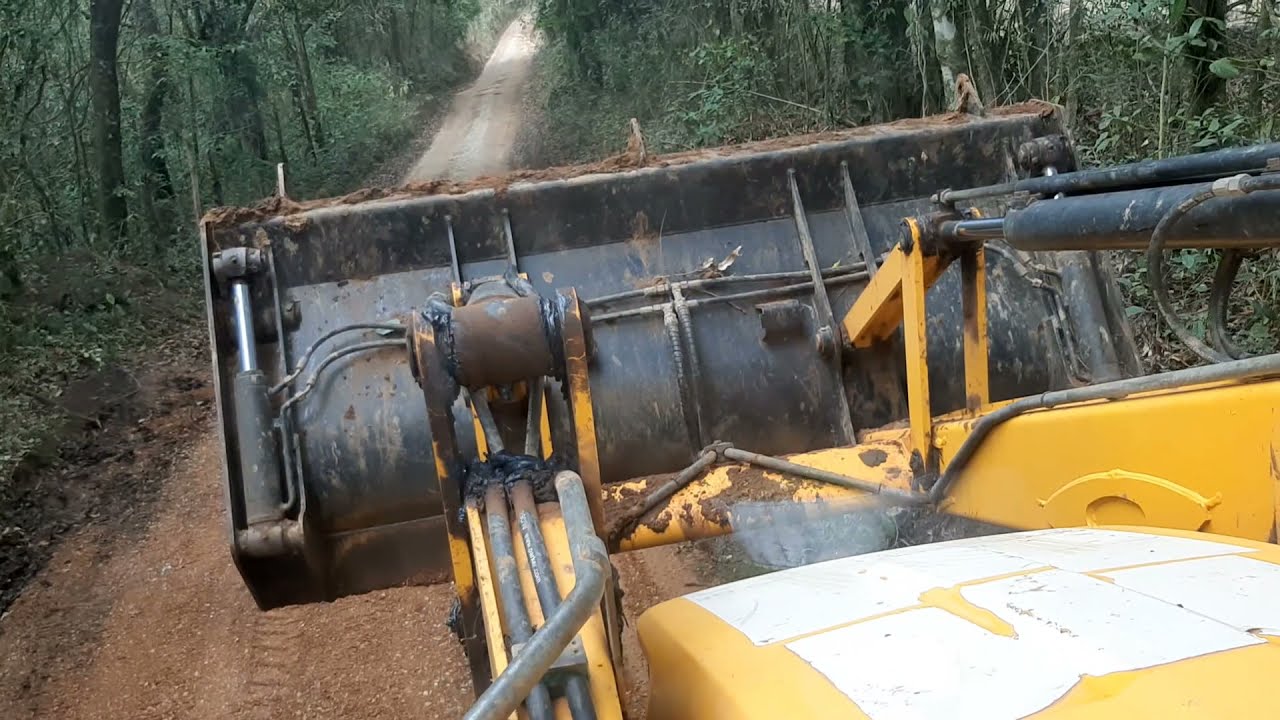 Retroescavadeira cobrindo pedra gra&uacute;da na estrada(Backhoe covering big rock on the road)