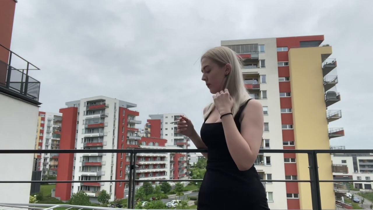 girl smoking cigarette in dress on her balcony