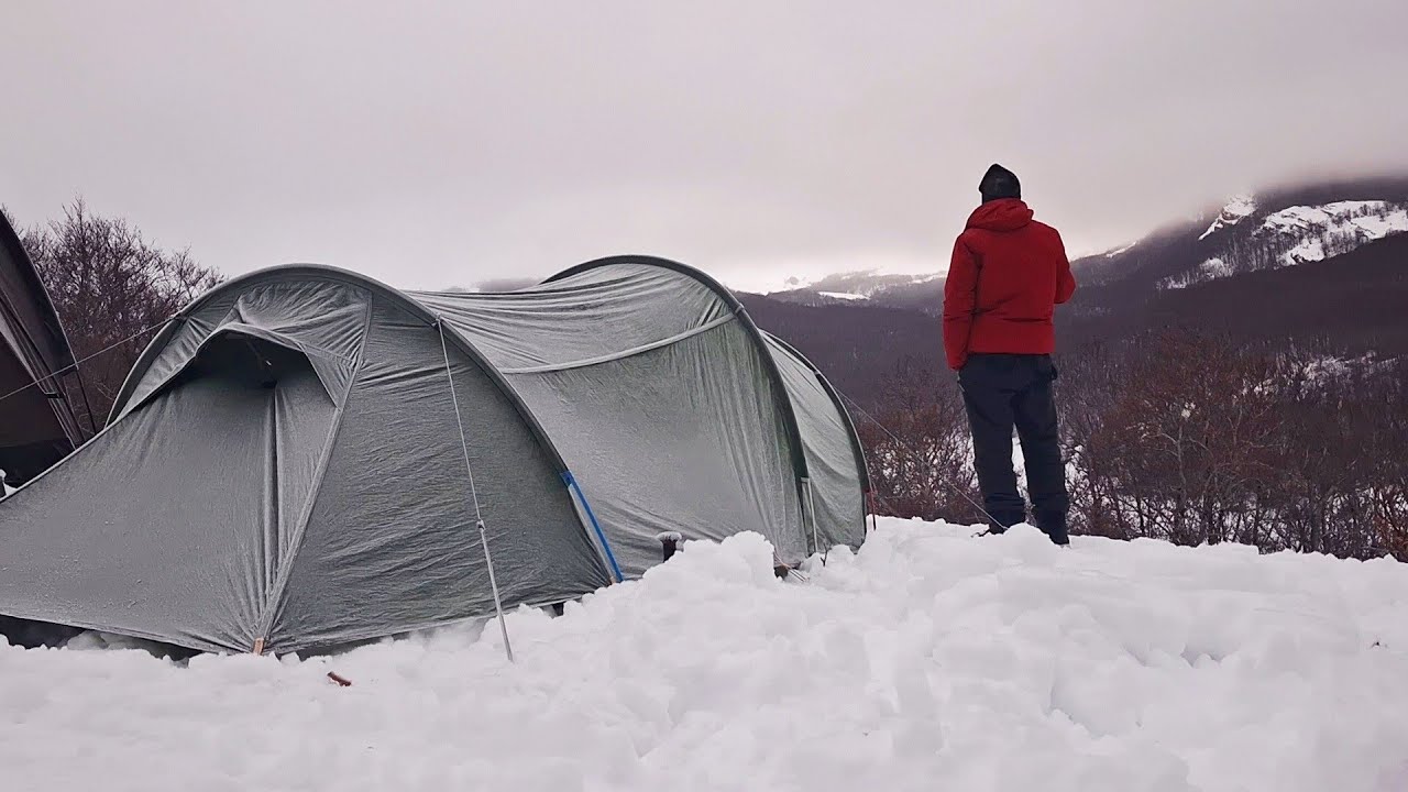 Notte in tenda nella neve cucinando carne sul fuoco.