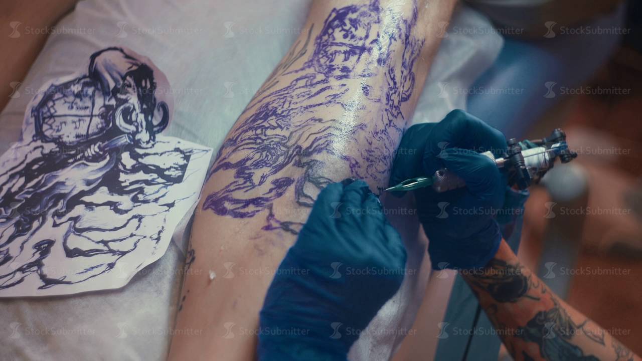 Tattoo artist make tattoo at the studio. Tattooing on foot