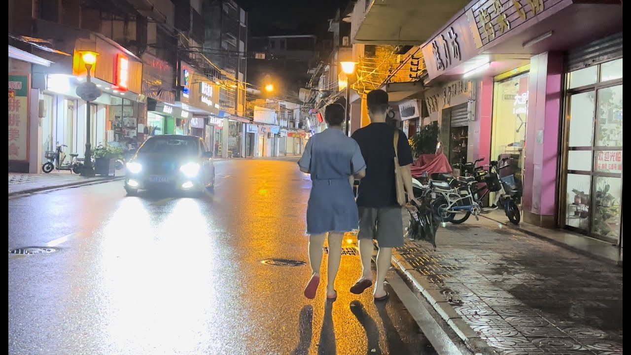 在江門市新會區古井鎮老街一個落雨的晚上街拍。只見昏暗的燈光下濕滑的馬路上，街上途人稀稀疏疏，大排檔、鋪面冷冷清清。