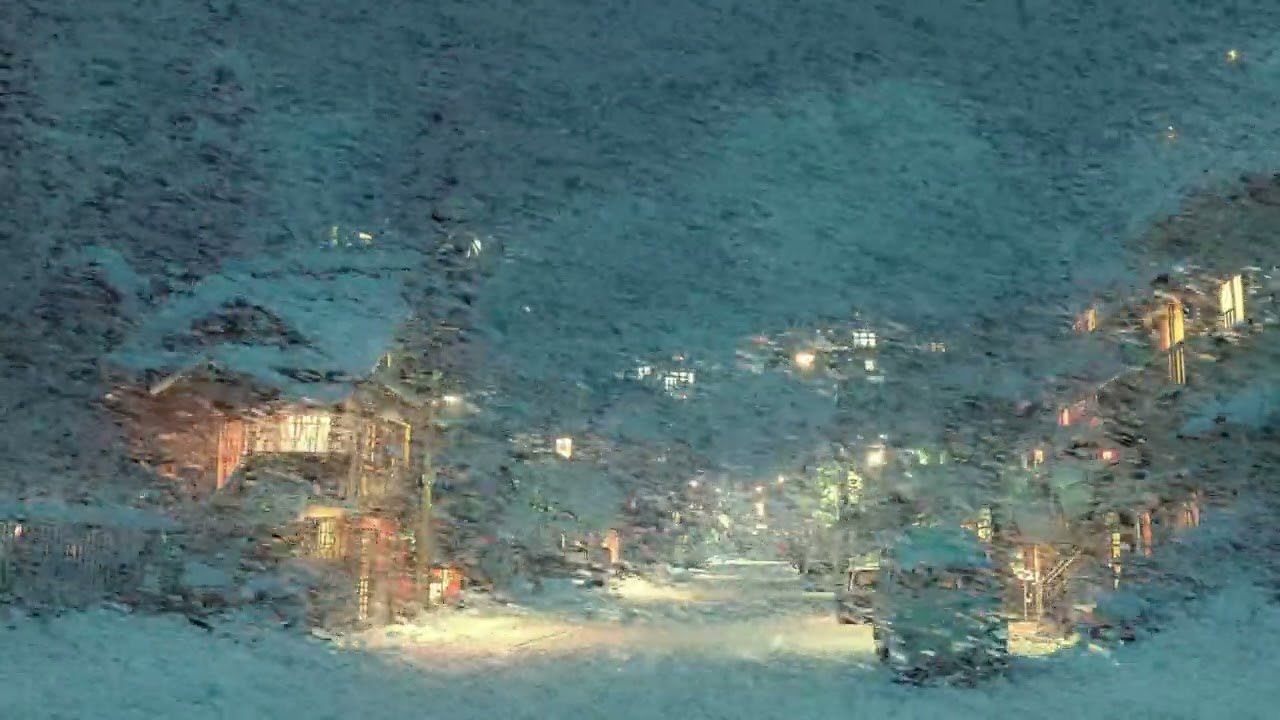Peaceful Snowy Mountain Town Street Glowing Warm Lights Under Heavy Winter Blizzard Night Scene
