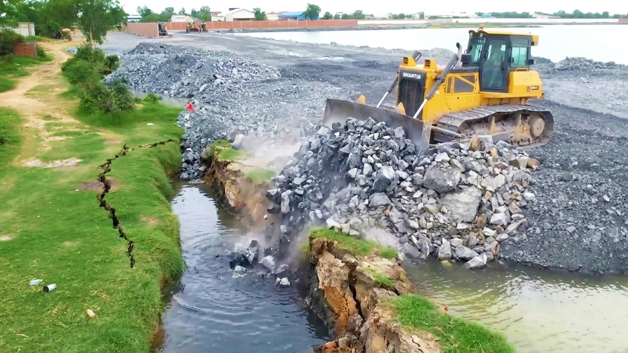 Perfect showing transaction stones filling in land sink area with smooth shantui dozer running