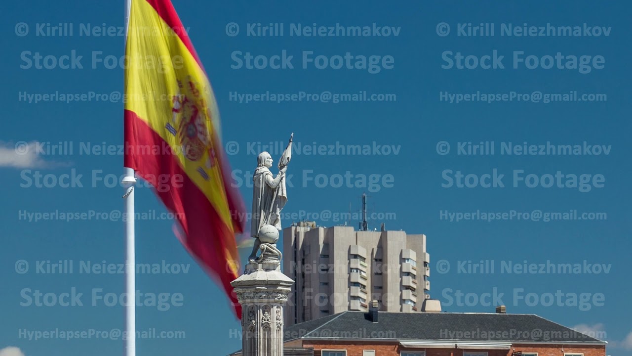 Spanish flag waves behind statue of Christopher Columbus timelapse, plaza de Colon in Madrid, Spain