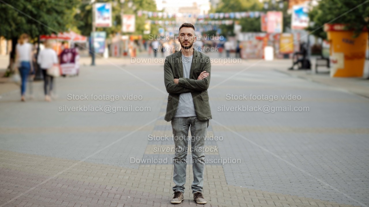 Timelapse of Young man standing still at sidewalk in crowd traffic stream with people moving fast