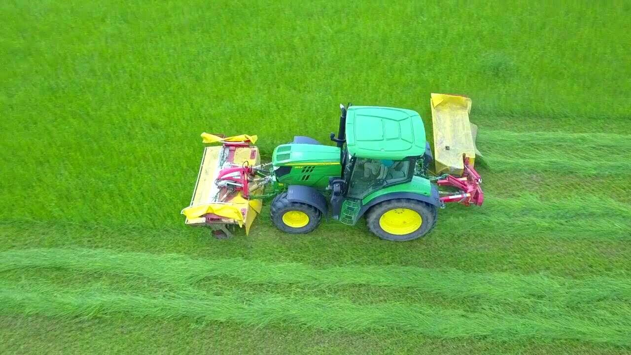 John Deere 6105R beim Mähen mit Pöttinger Mähkombi