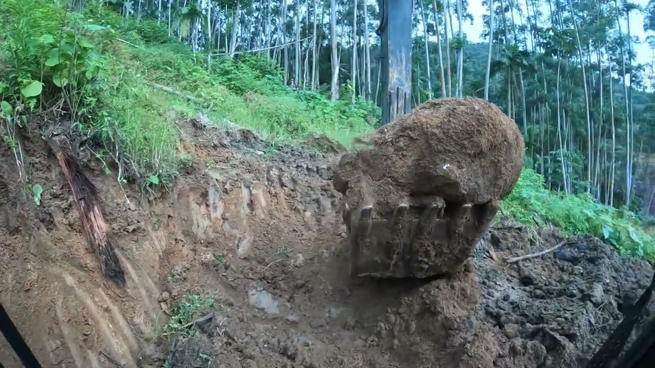 Escavadeira abrindo estrada com muita lama e pedras