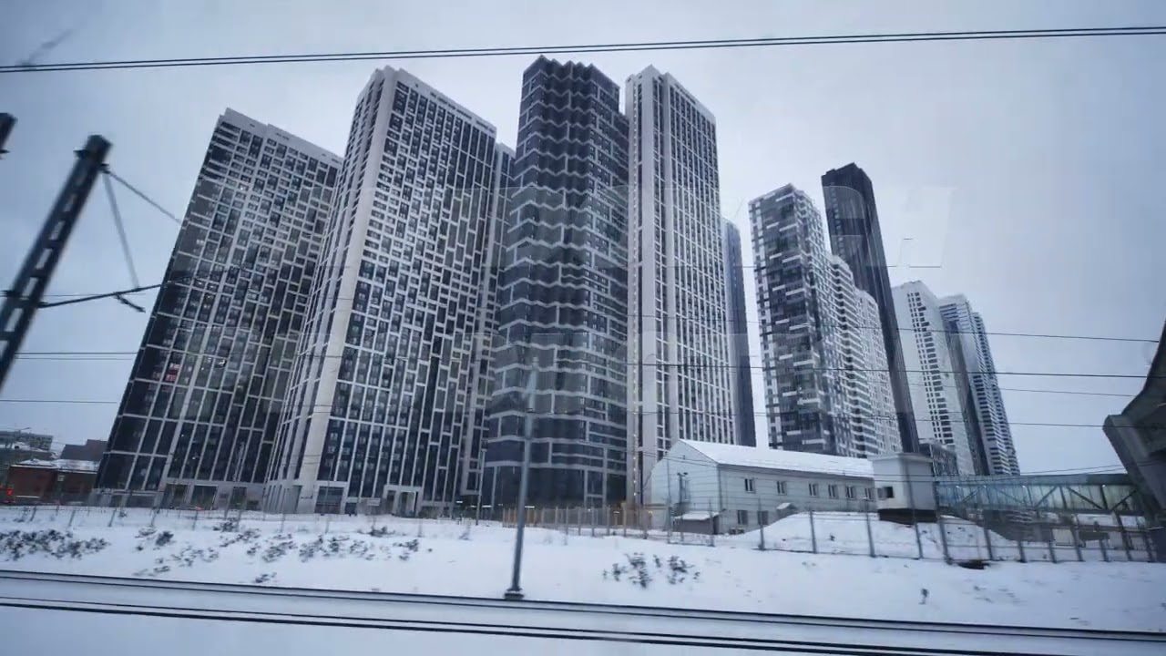 Modern skyscrapers rising above snowy urban landscape viewed from moving train in Moscow