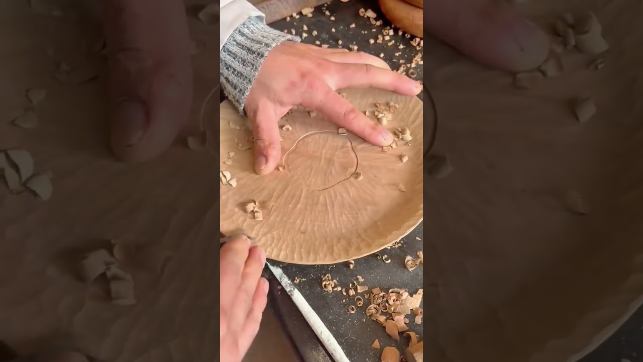 using a small chisel to carve patterns on wooden plate