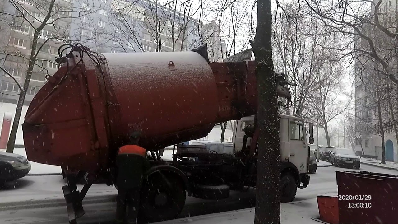 Мусоровоз зимой. Замело контейнеры с мусором. Загрузка мусора в снегопад.