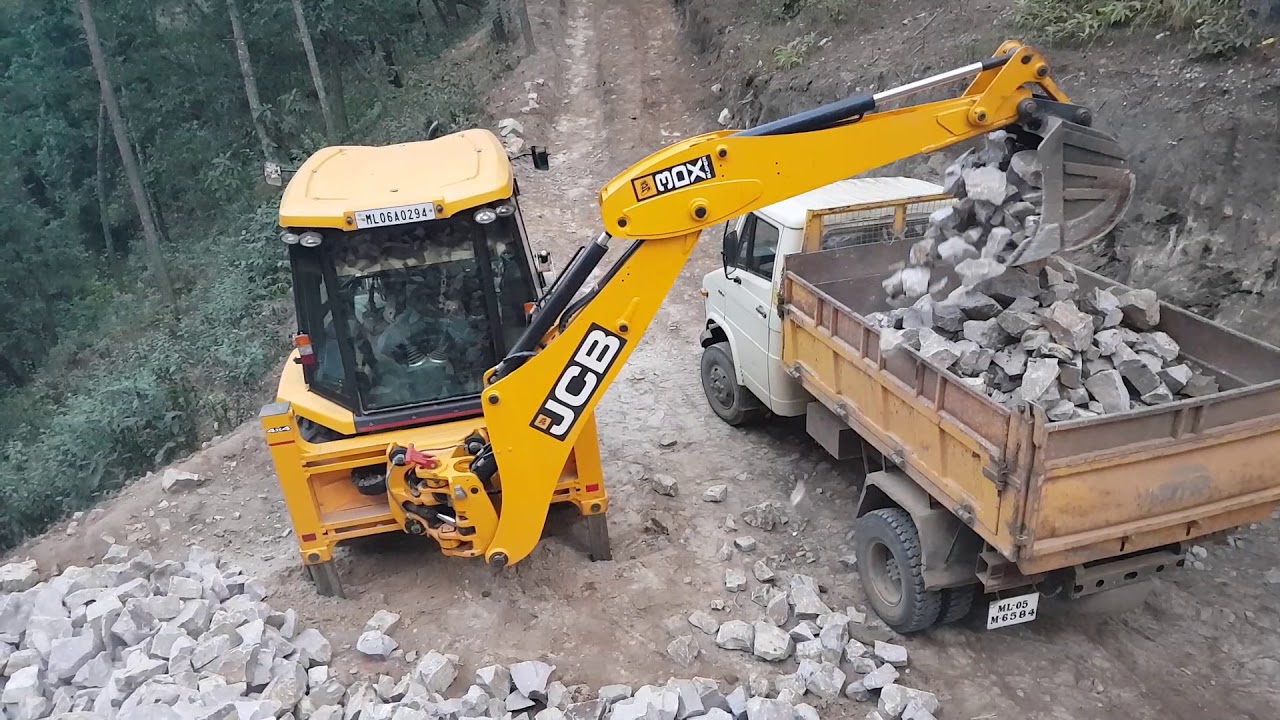 Jcb backhoe loading stones  into a dump truck ## jcb 3dx super loading stones in a stone quarry