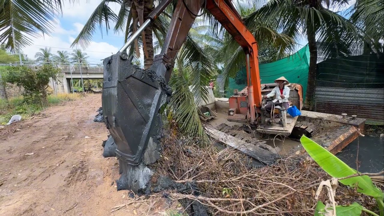 xe cuốc 03 gàu mỏ vịt múc đất lên làm lộ trong kinh nhỏ