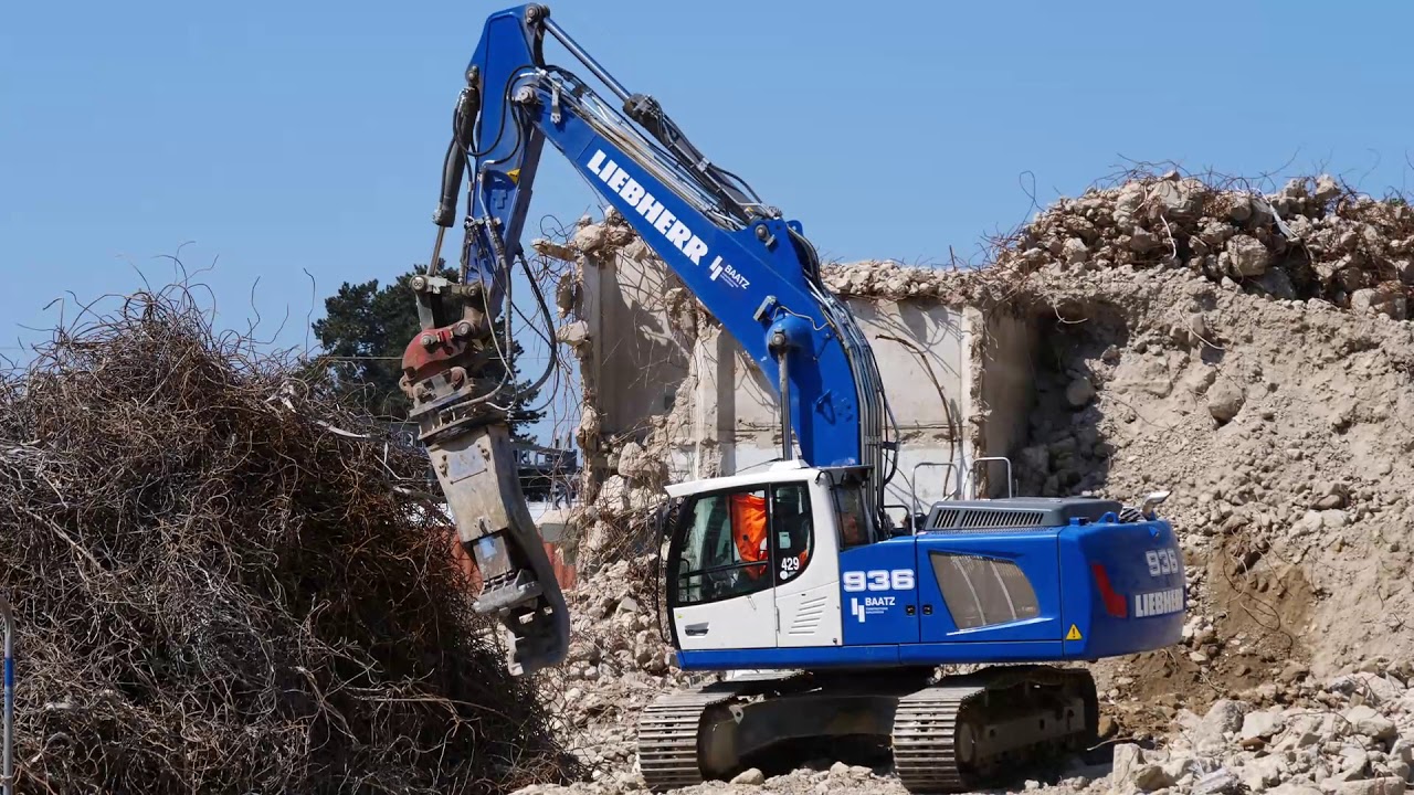 Liebherr R936 crushing concrete and stacking rebar.