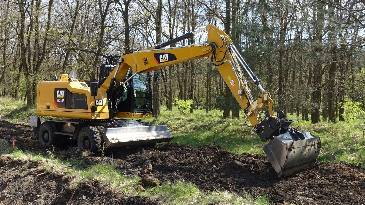 New CAT M314F wheeled excavator grading clay