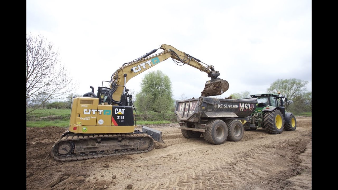 Cat 314 E mit Oil Quick beim Erdbau belädt John Deere 8285 R mit Mulde