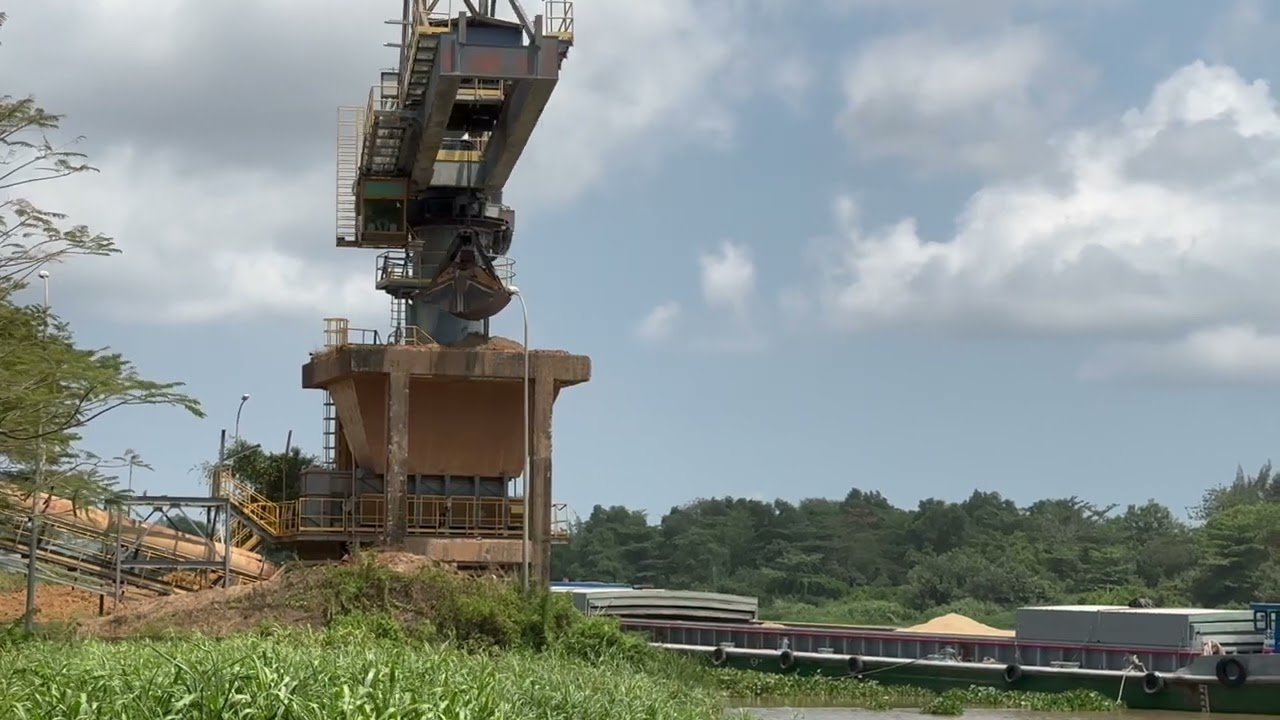 Swing crane transports sand from barge to storage