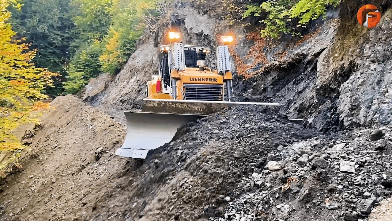 Operatori pricepuți de excavatoare construiesc drumuri pe un munte abrupt
