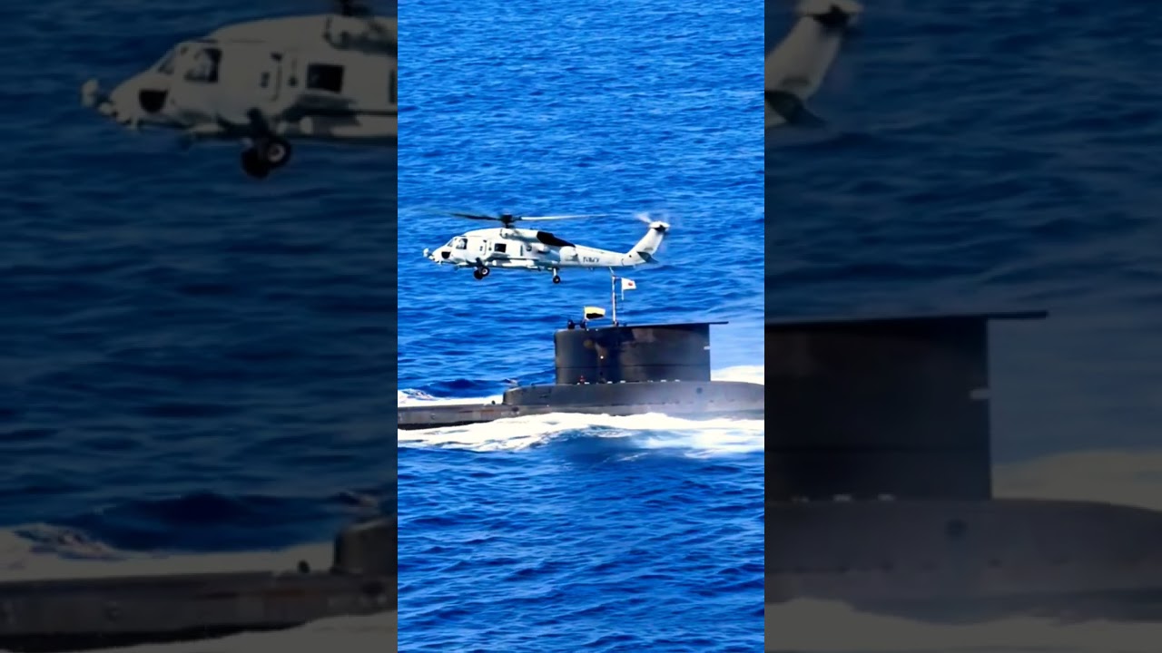 A stunning encounter in the open ocean! An MH-60R Seahawk helicopter flies low over a surfaced....