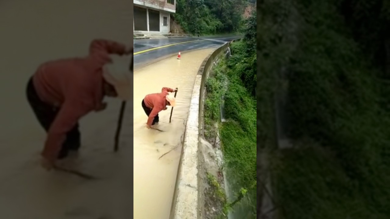 A man unclogs a drain with a plunger on a highway  #floodrescue #satisfying #rain #trending #shorts