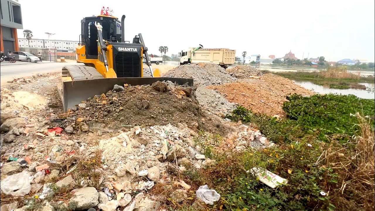Great job !! Expert bulldozer working push soil landfill flooded with dump truck wheel 10 unloading.