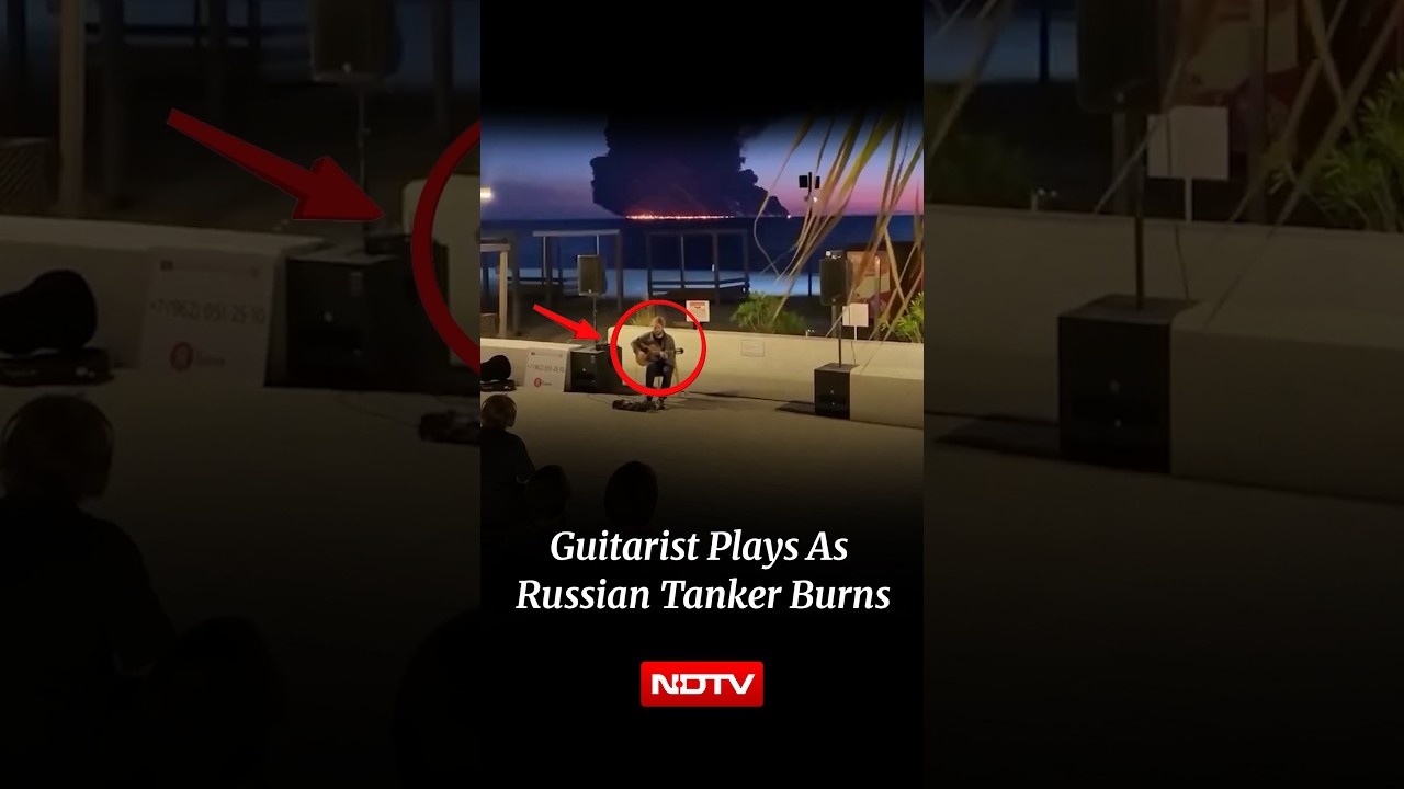 Russian Man Plays Guitar As Drone Hit Oil Tanker Burns In The Background