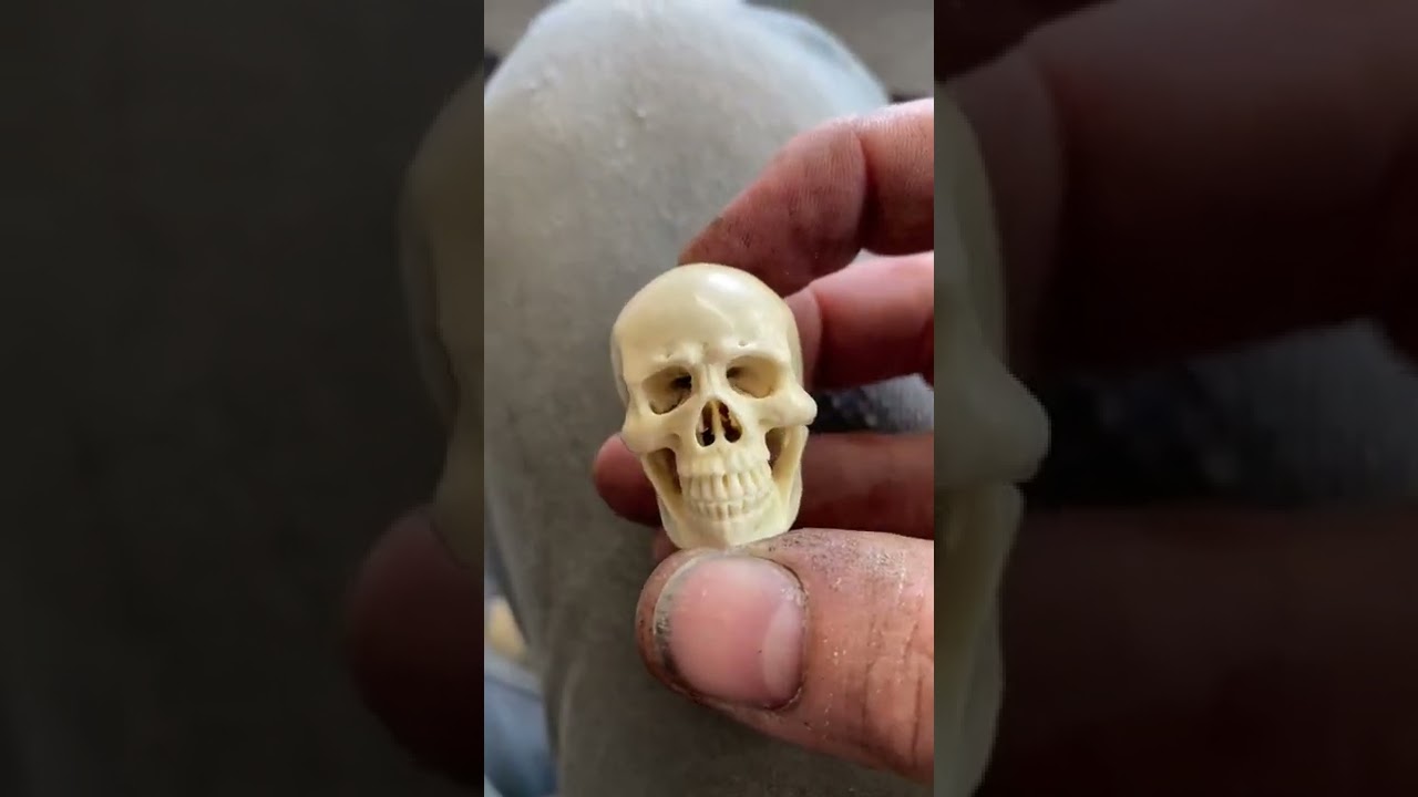 Carving an antler skull pendant.