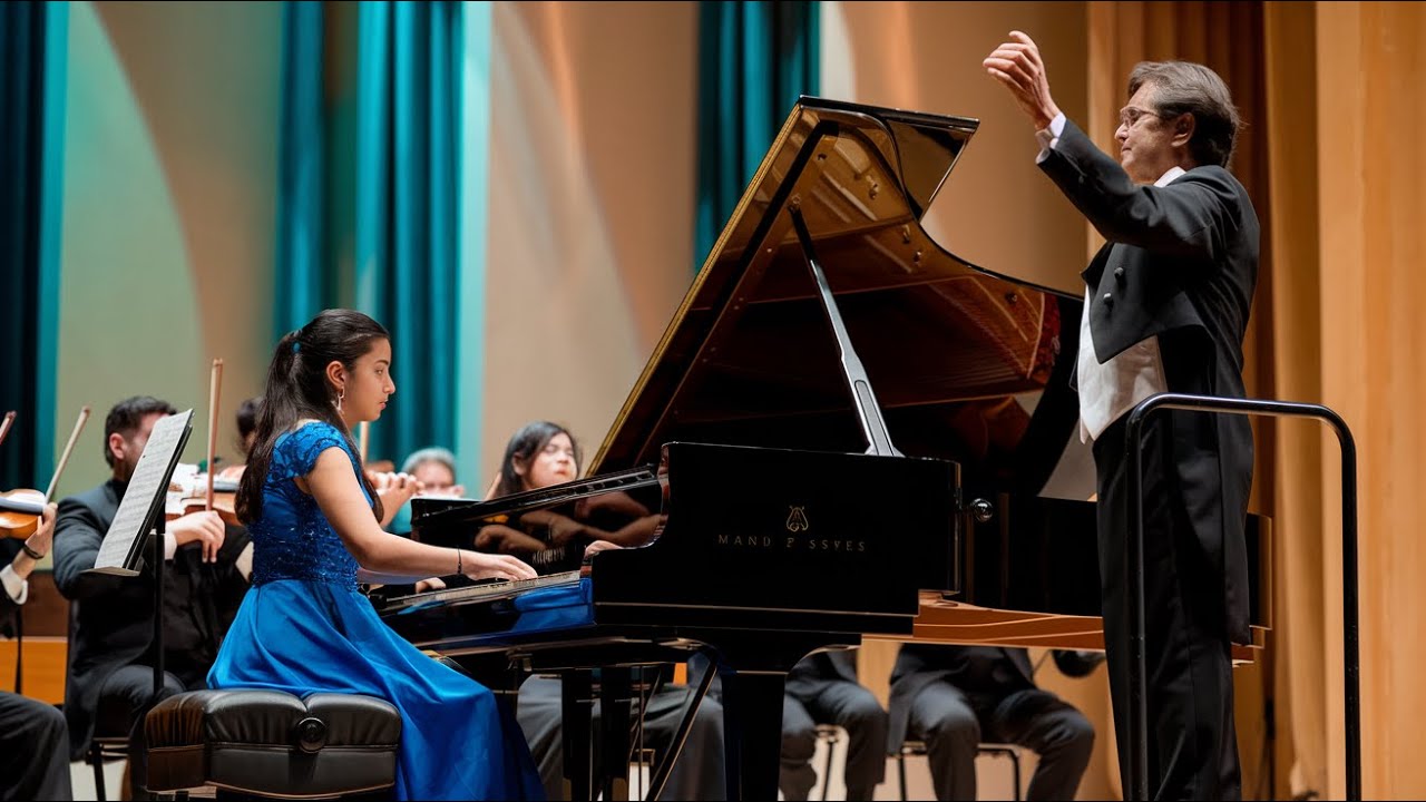 An orchestra conductor challenges a young Mexican woman to play Piano but her solo stops the concert